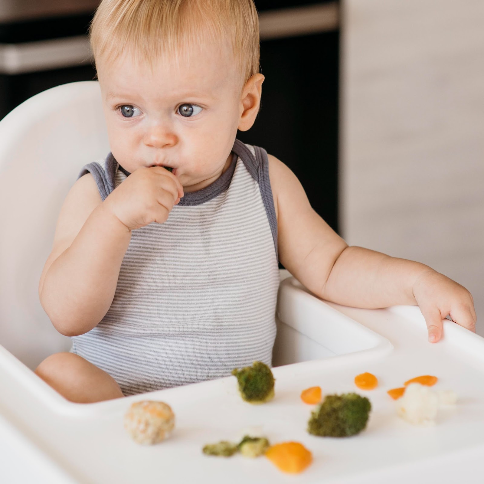 A little boy eating on his high chair