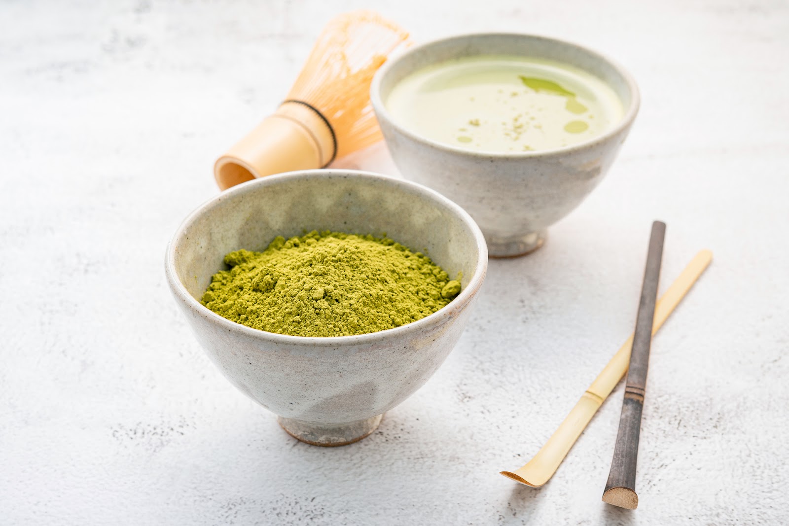 Doua recipiente rotunde, unul cu ceai matcha, celalalt cu pudra de matcha