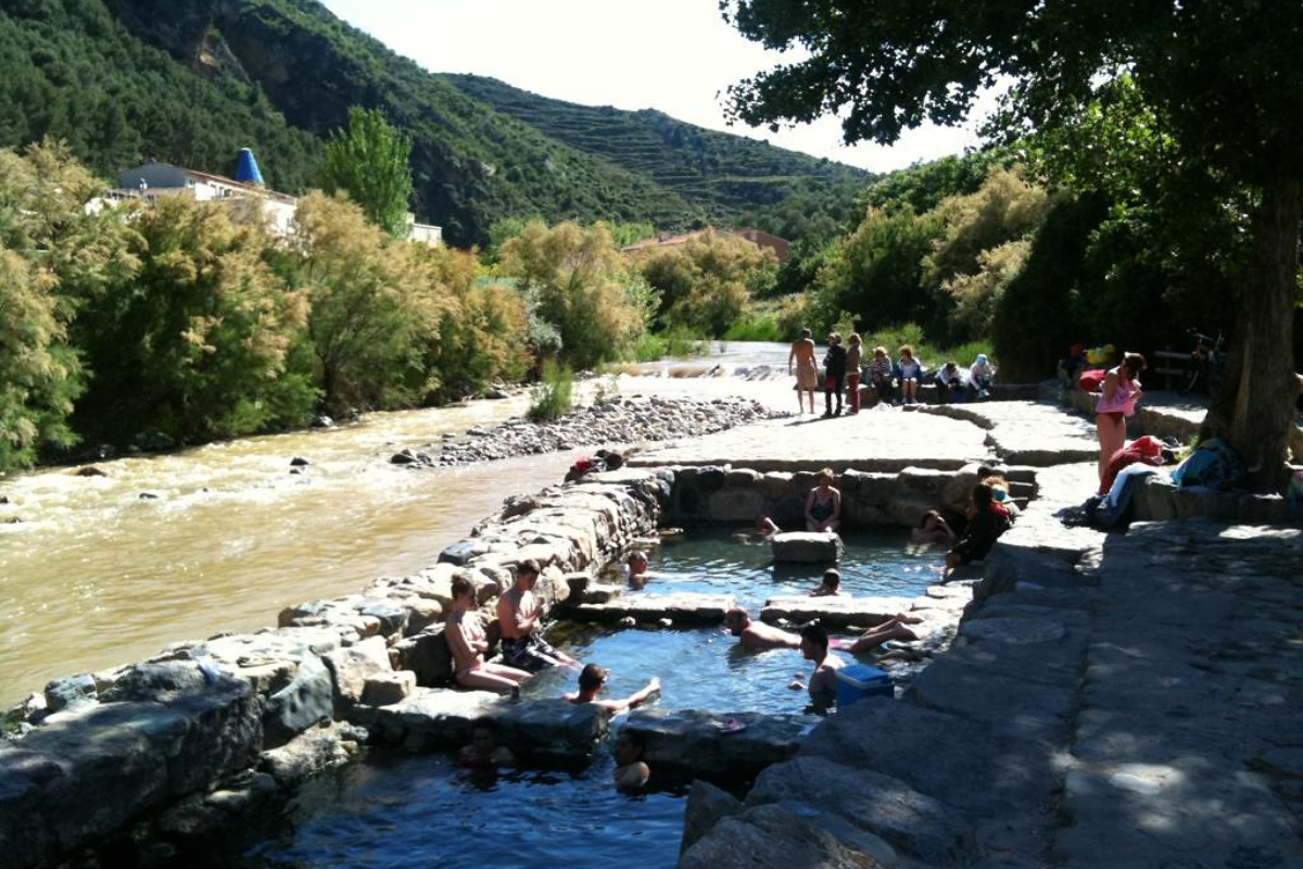 People are enjoying in the water while some are sitting on the stones near water in Cartago