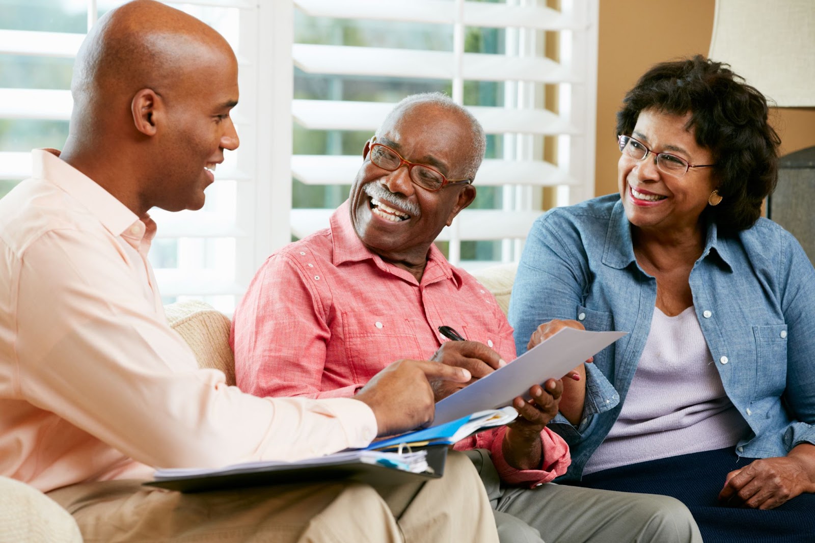 A young professional explains tax paperwork to a smiling older couple.