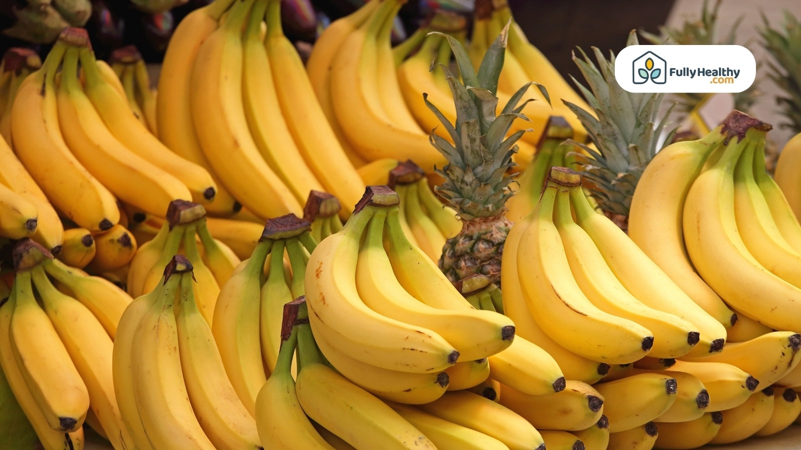 Bunches of bananas stacked with pineapples at a market