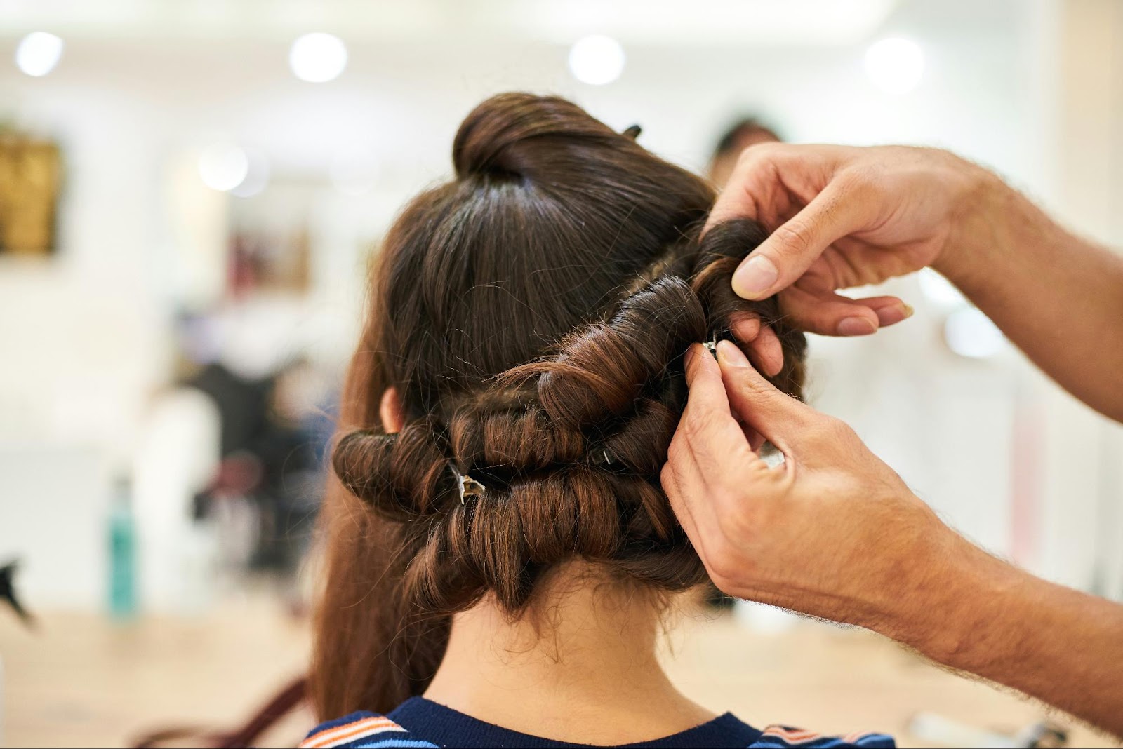 Stylist securing clip-in hair extensions into sectioned hair