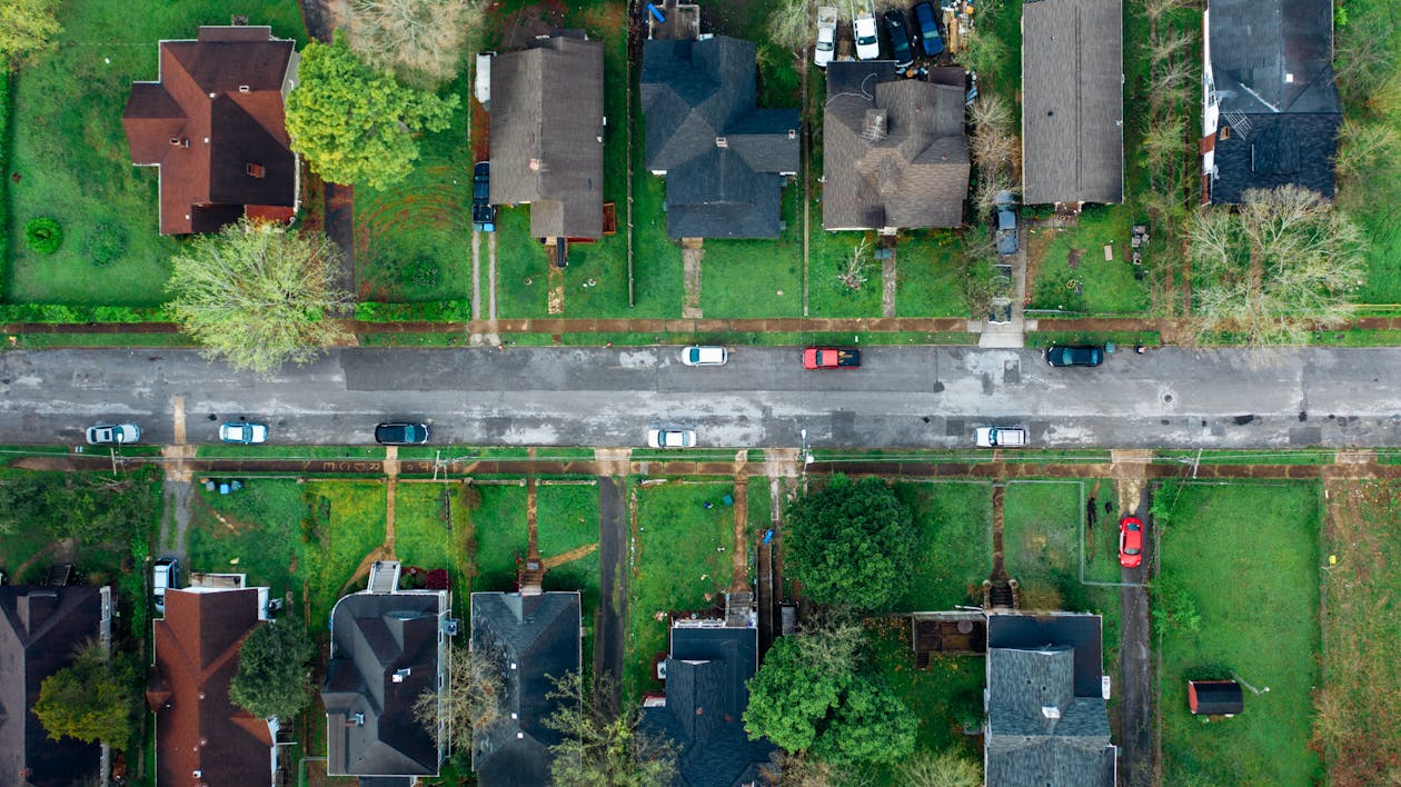 Aerial view of a suburban neighborhood with multiple houses surrounded by green lawns and mature trees.