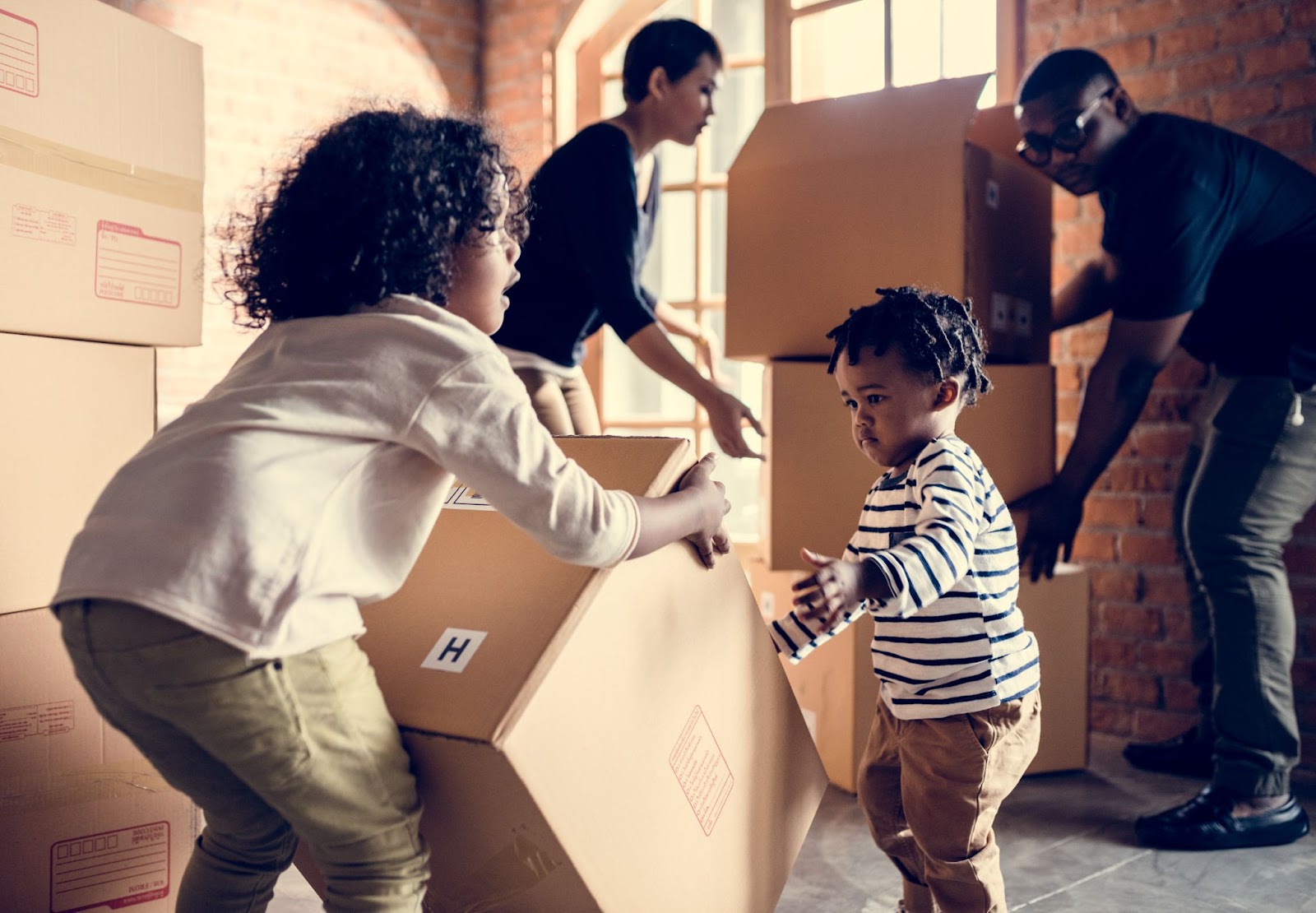 Kids tilting a moving box with parents in background