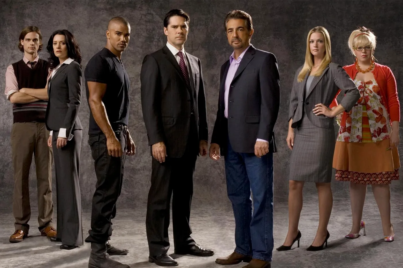 Equipo completo de detectives de la serie 'Criminal Minds', posando juntos en un fondo oscuro con expresiones serias.