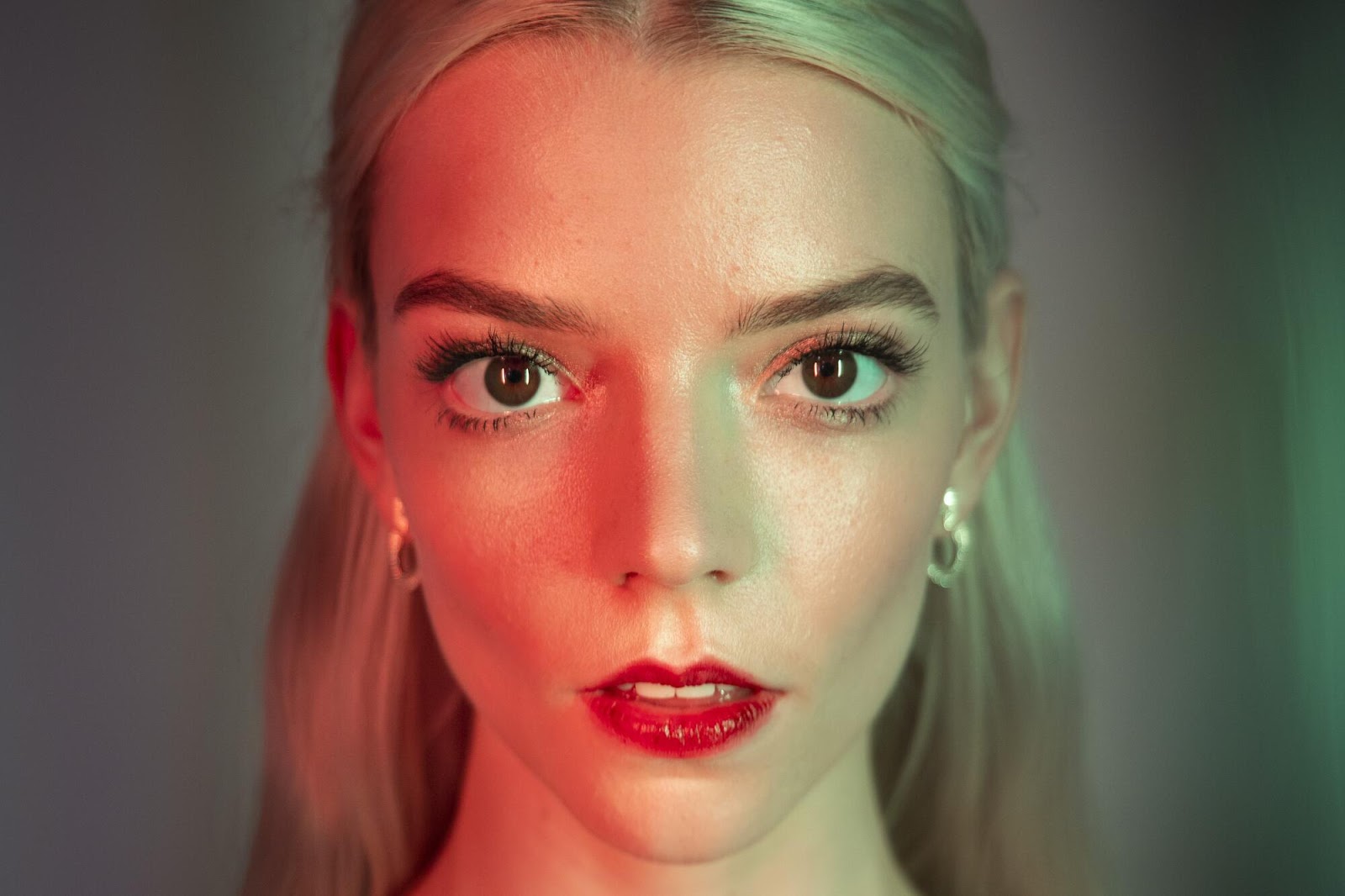 Primer plano de Anya Taylor-Joy con maquillaje dramático y luz ambiental, destacando su mirada intensa.