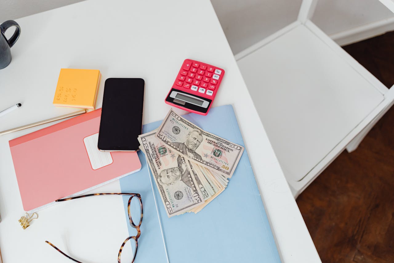 A desk with a tax form and calculator, a money and a mobile phone