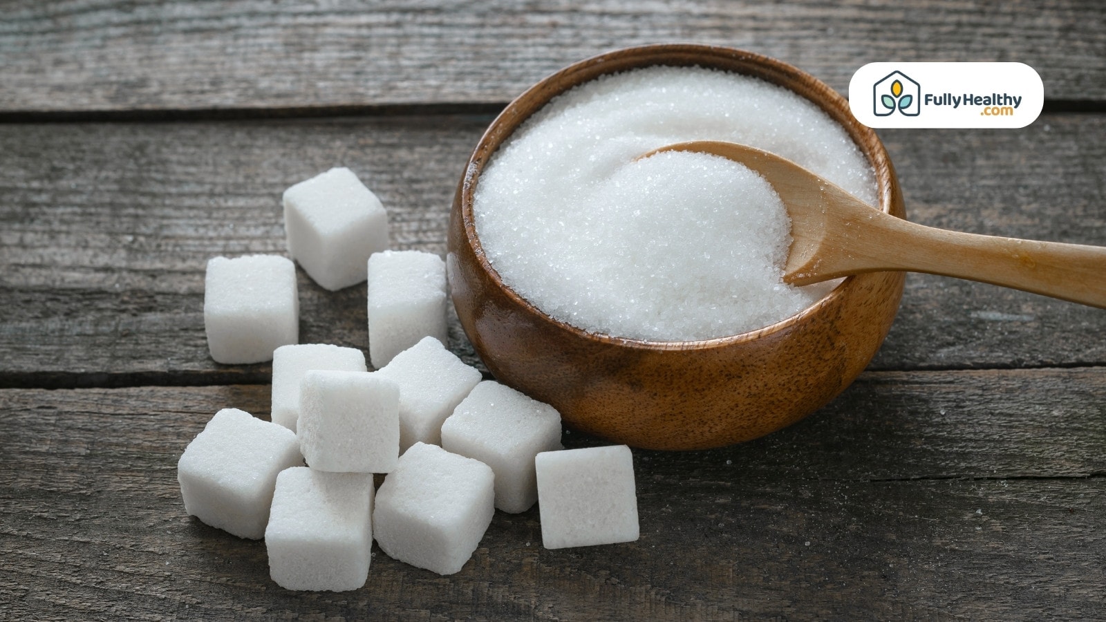 White sugar cubes and granulated sugar in wooden bowl with spoon