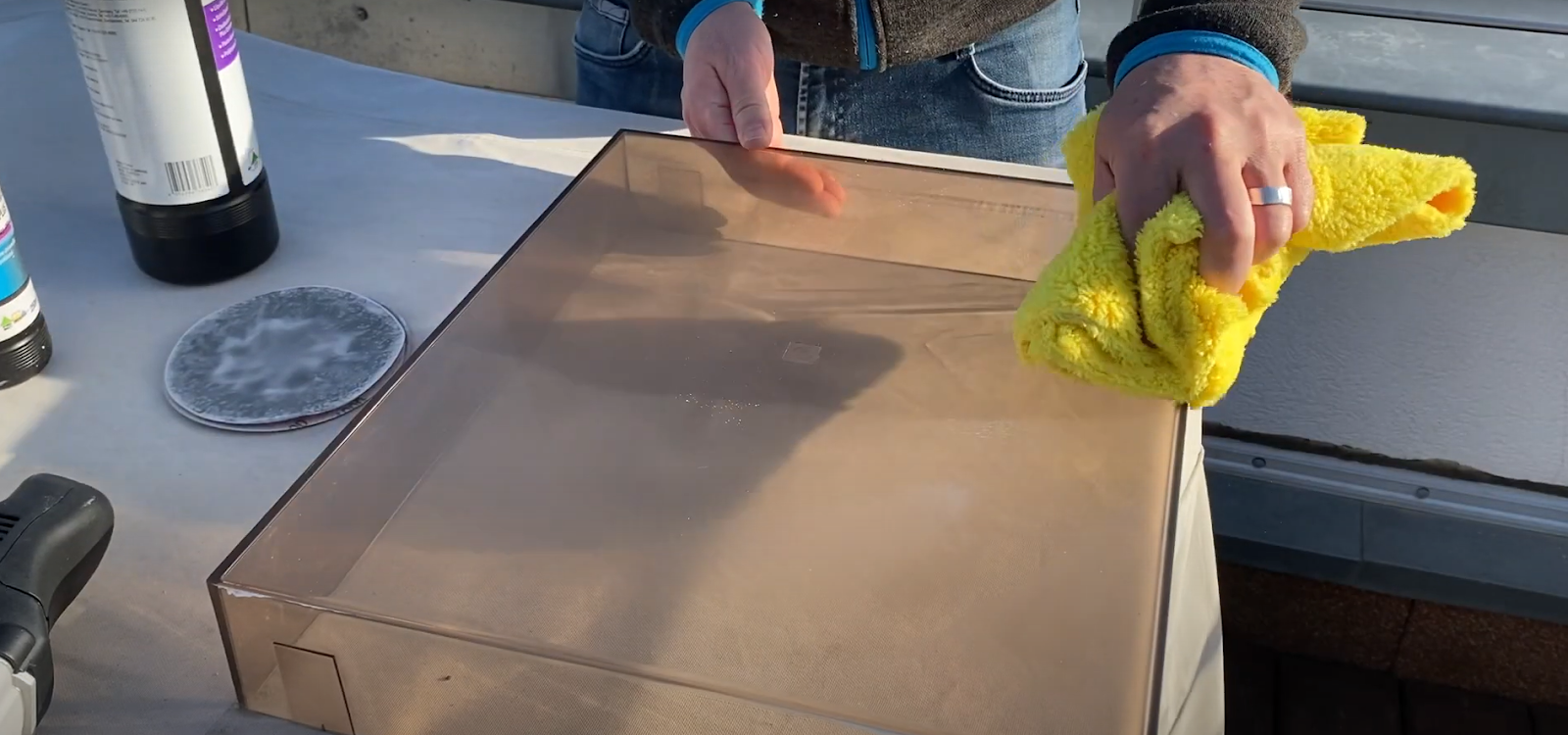 Polishing a turntable dust cover with a microfiber cloth.