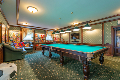 Pool table in a game room with comfy furniture around the room.