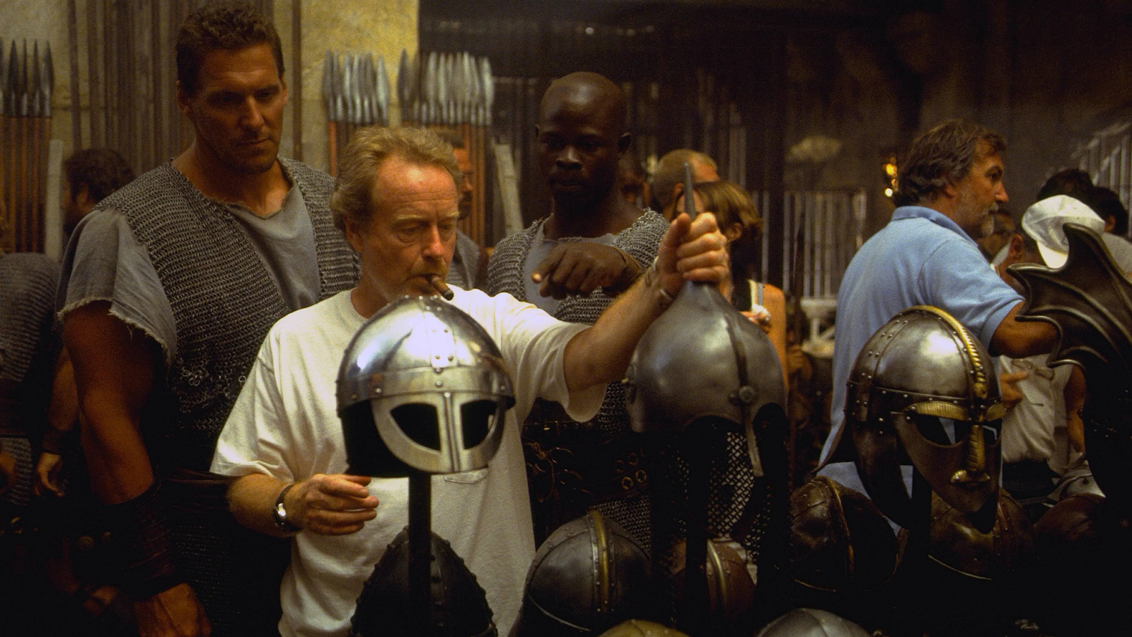 Director Ridley Scott revisando cascos de gladiadores en el set de filmación, rodeado de actores y equipo de producción durante el rodaje de Gladiator.