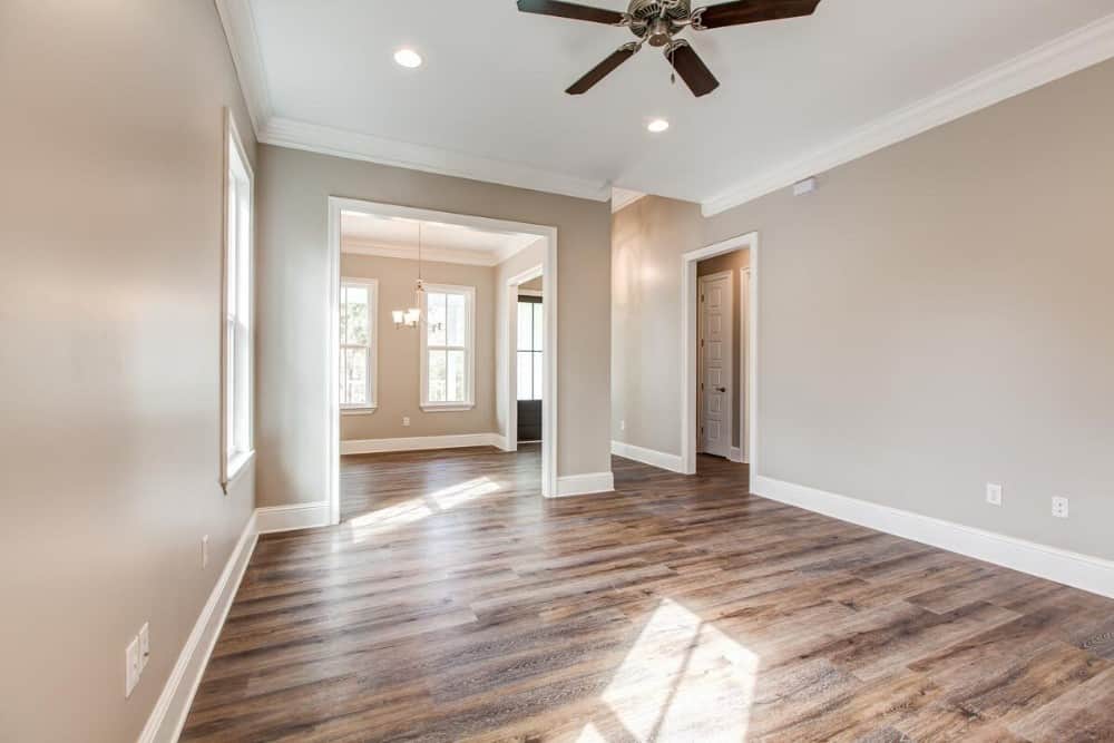 Living area with hardwood flooring and gray walls line with white moldings.