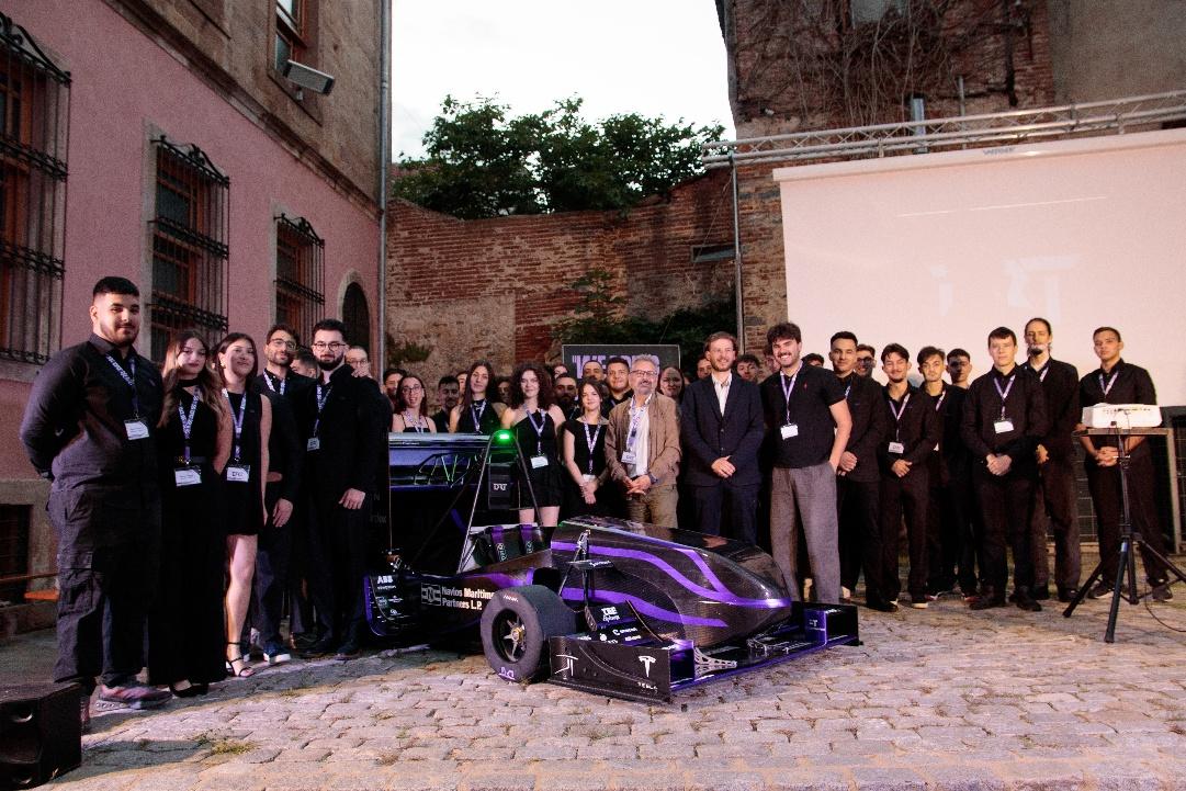 A group of people standing around a race car

AI-generated content may be incorrect.