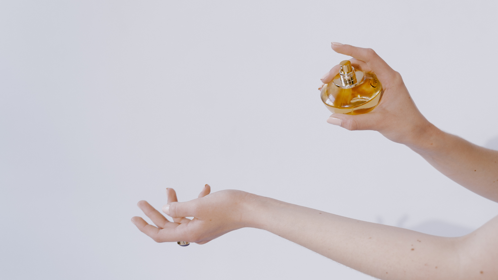 Seseorang menyemprotkan parfum di pergelangan tangannya/Sumber: Canva