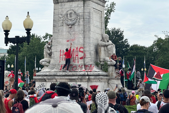 A group of people with graffiti on a monument

Description automatically generated