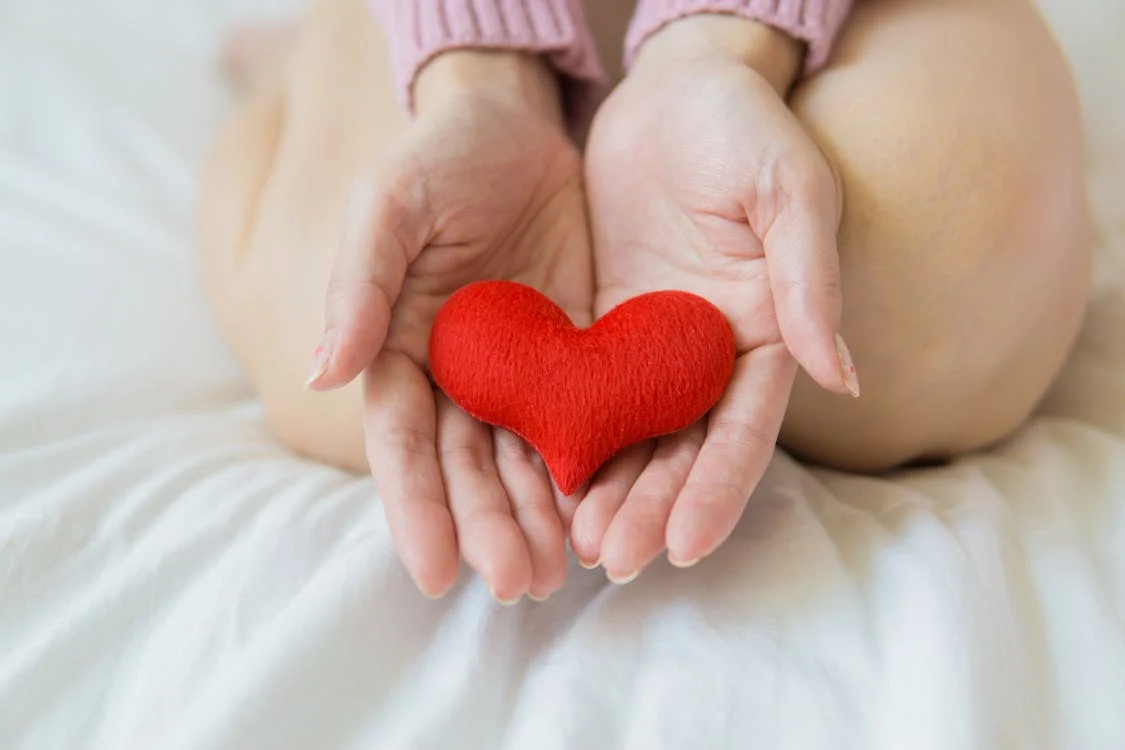 Two hands holding a red fabric heart shape. The photo represents how Primal Trust™ can help you with Integrative Body-Mind Training