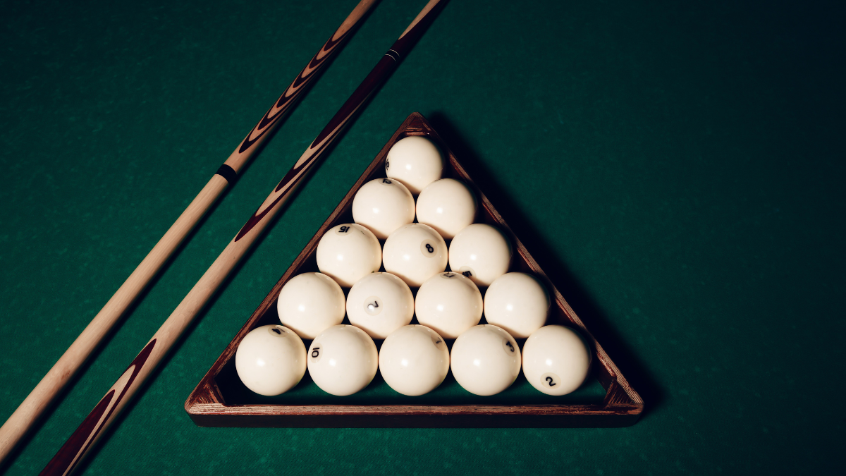 This image displays a neatly arranged triangle of white billiard balls on a green felt table, accompanied by two wooden cue sticks.