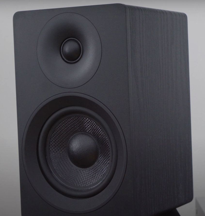 Close-up of a black bookshelf speaker with tweeter and woofer.