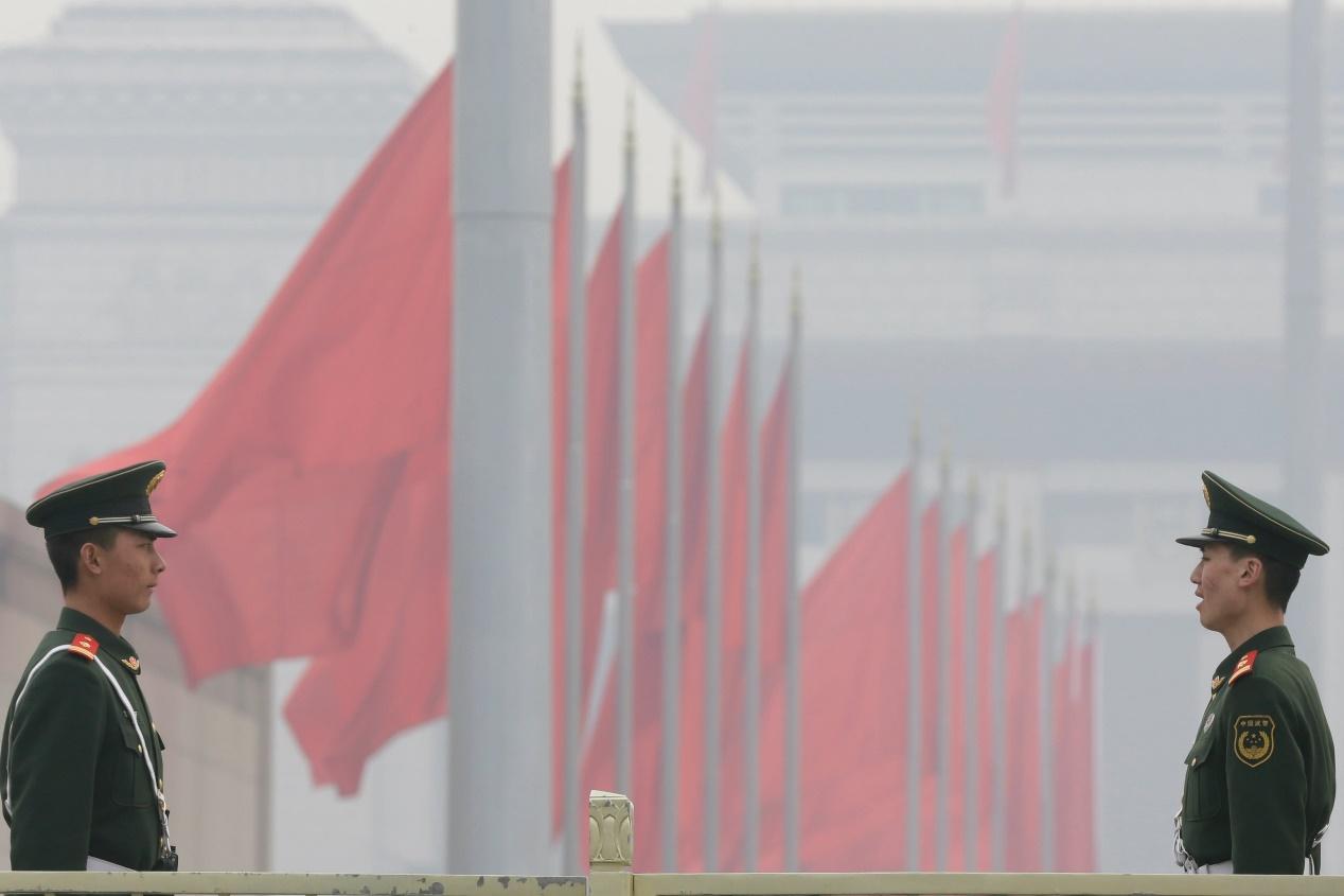 Paramilitary police officers stand guard on Tiananmen Square on a hazy day in Beijing