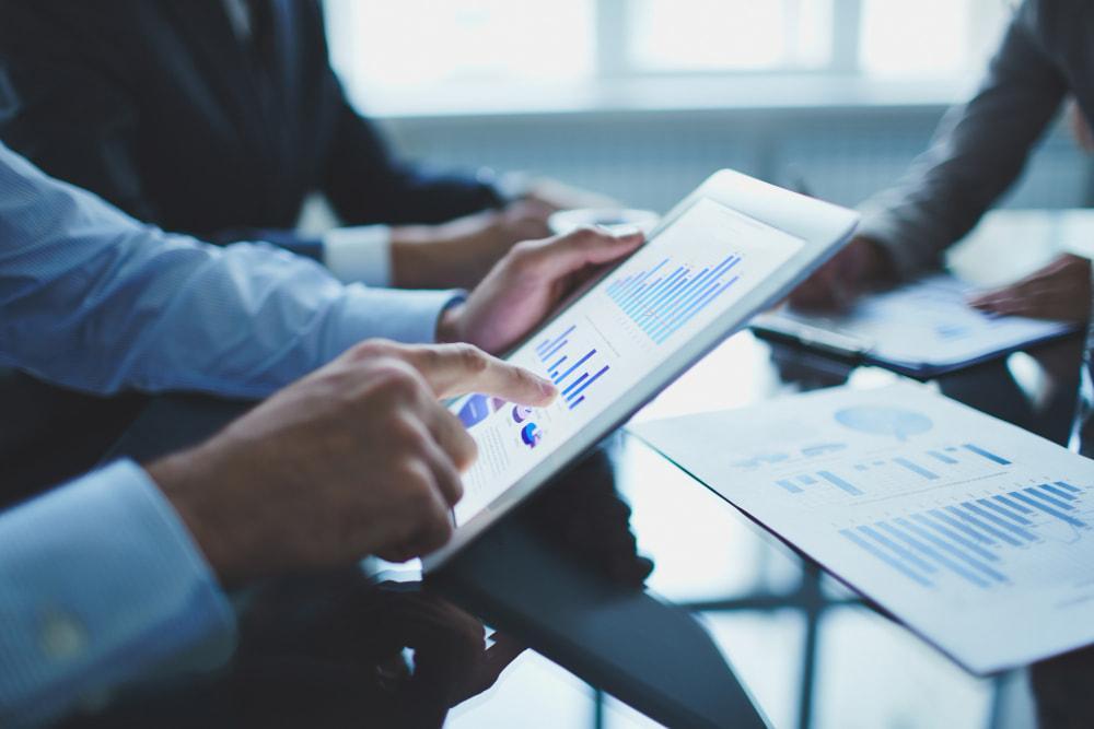 A person analyzing graphs and reports on a tablet.