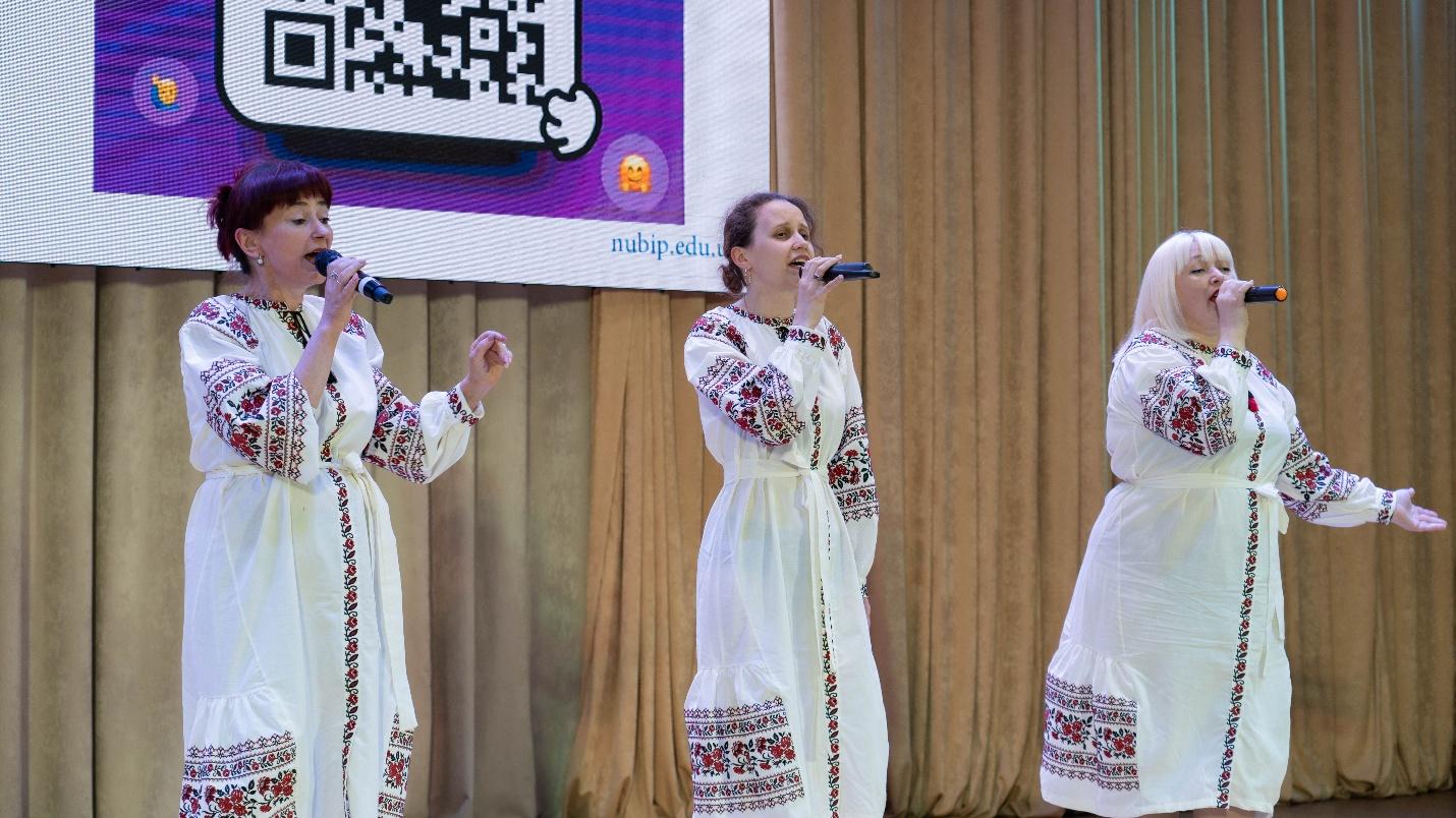 A group of women singing on stageAI-generated content may be incorrect.