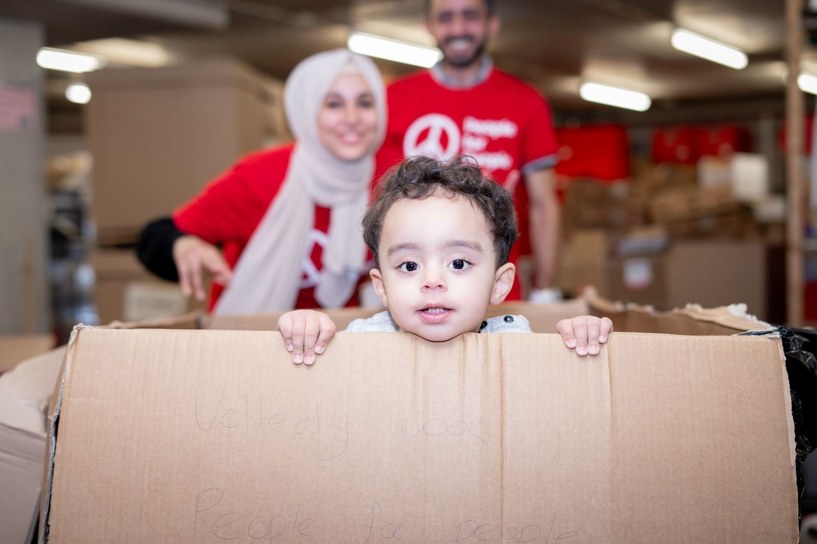 A picture of Issa playing in a cardboard box in the People for People warehouse.