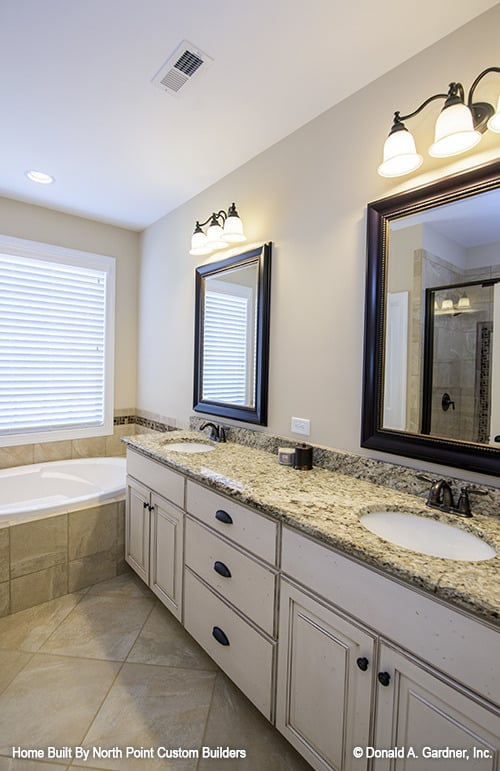 Primary bathroom with a drop-in bathtub and a dual sink vanity paired with framed mirrors.