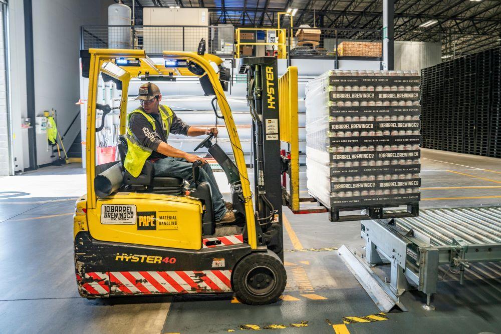 A worker using a yellow forklift