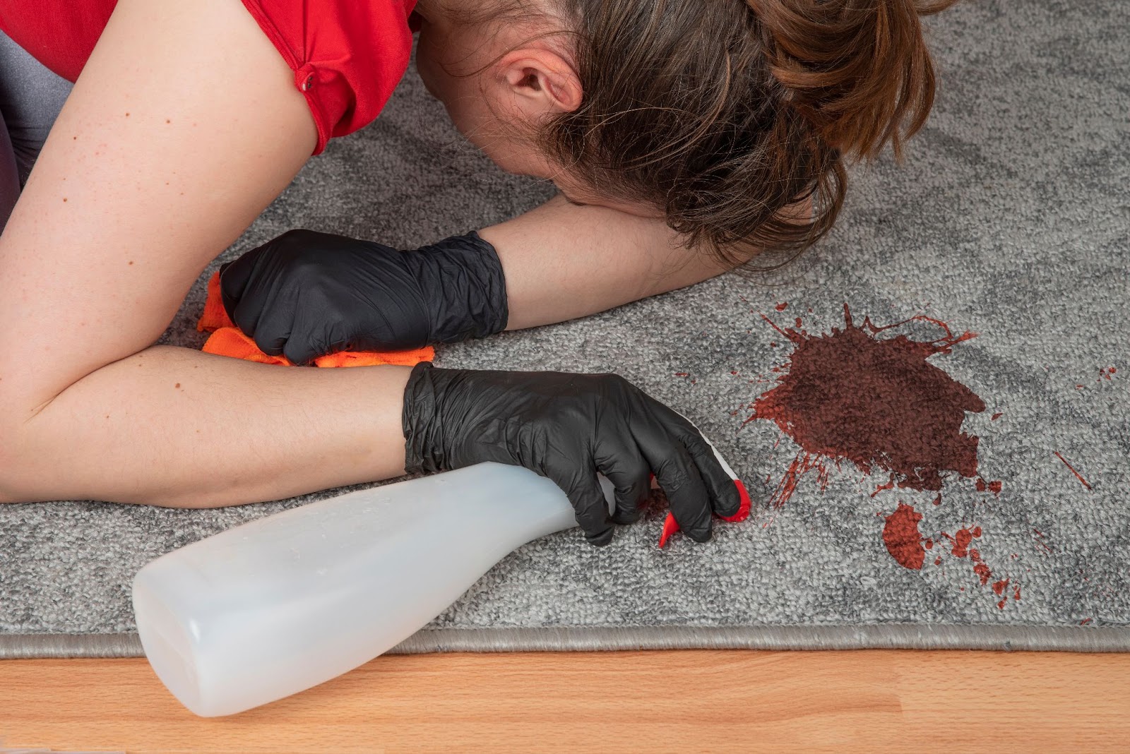 Woman trying to clean red blood stain out of carpet
