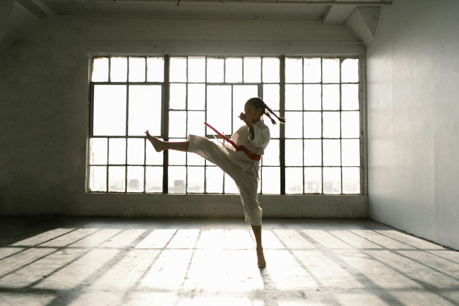 A young martial arts student performing a flying kick, with one foot off the ground and the other firmly planted for balance