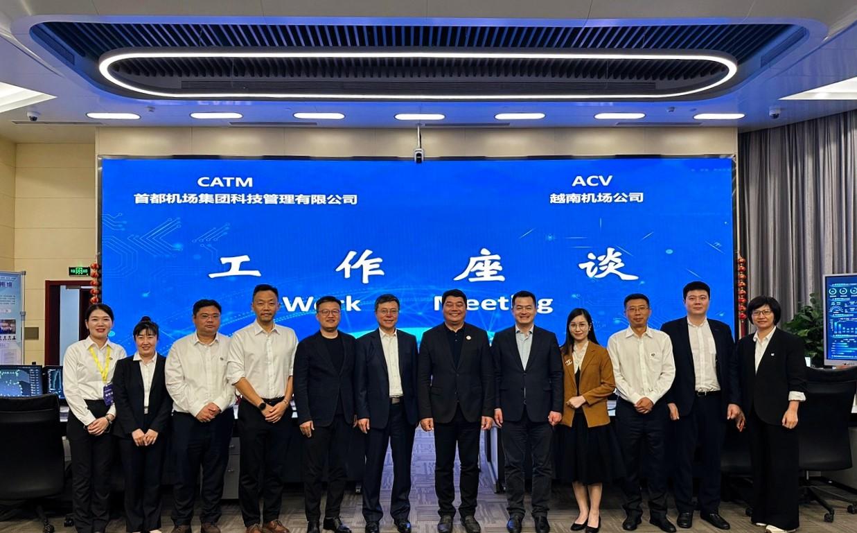 A group of people standing in front of a large blue signDescription automatically generated