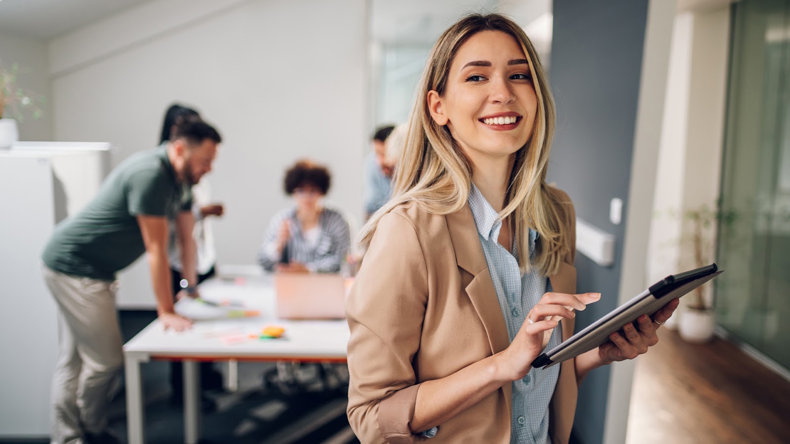 Group of professionals smiling and working in a bright modern office showcasing a fun & welcoming workplace environment