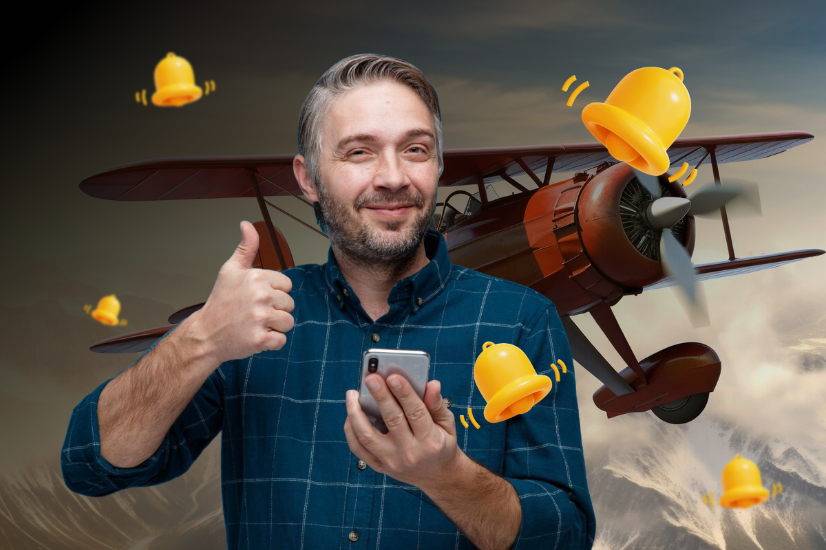 A man smiling while holding a cell phone and giving a thumbs up gesture, expressing approval and satisfaction.