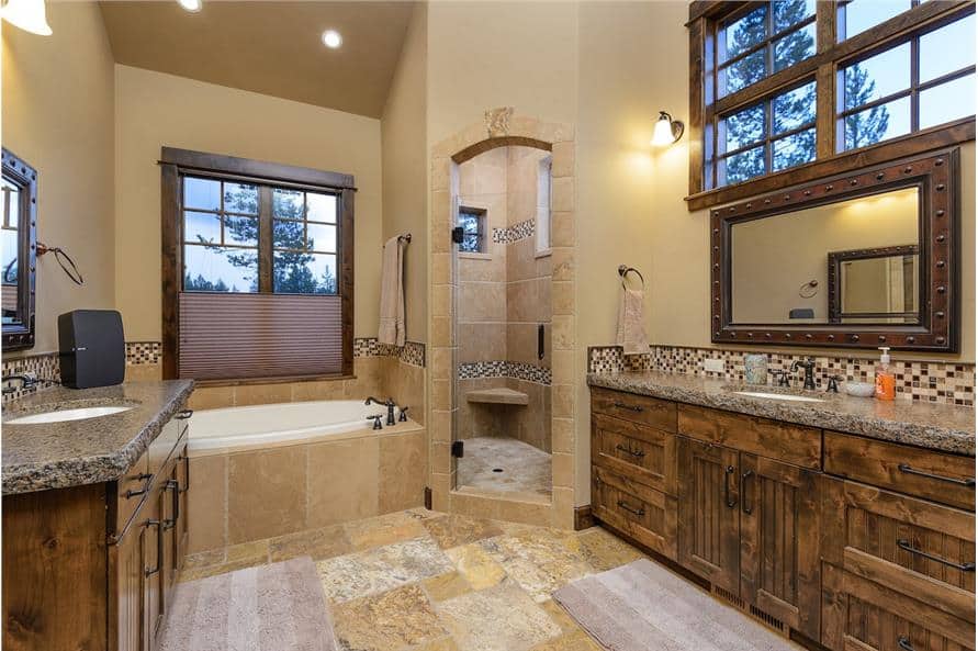 Primary bathroom with his and her sink vanities, a deep soaking tub, and a walk-in shower with an arched door.