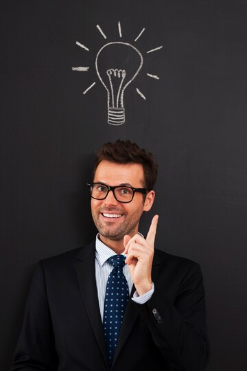 A smiling man pointing upwards to a drawing of a lightbulb