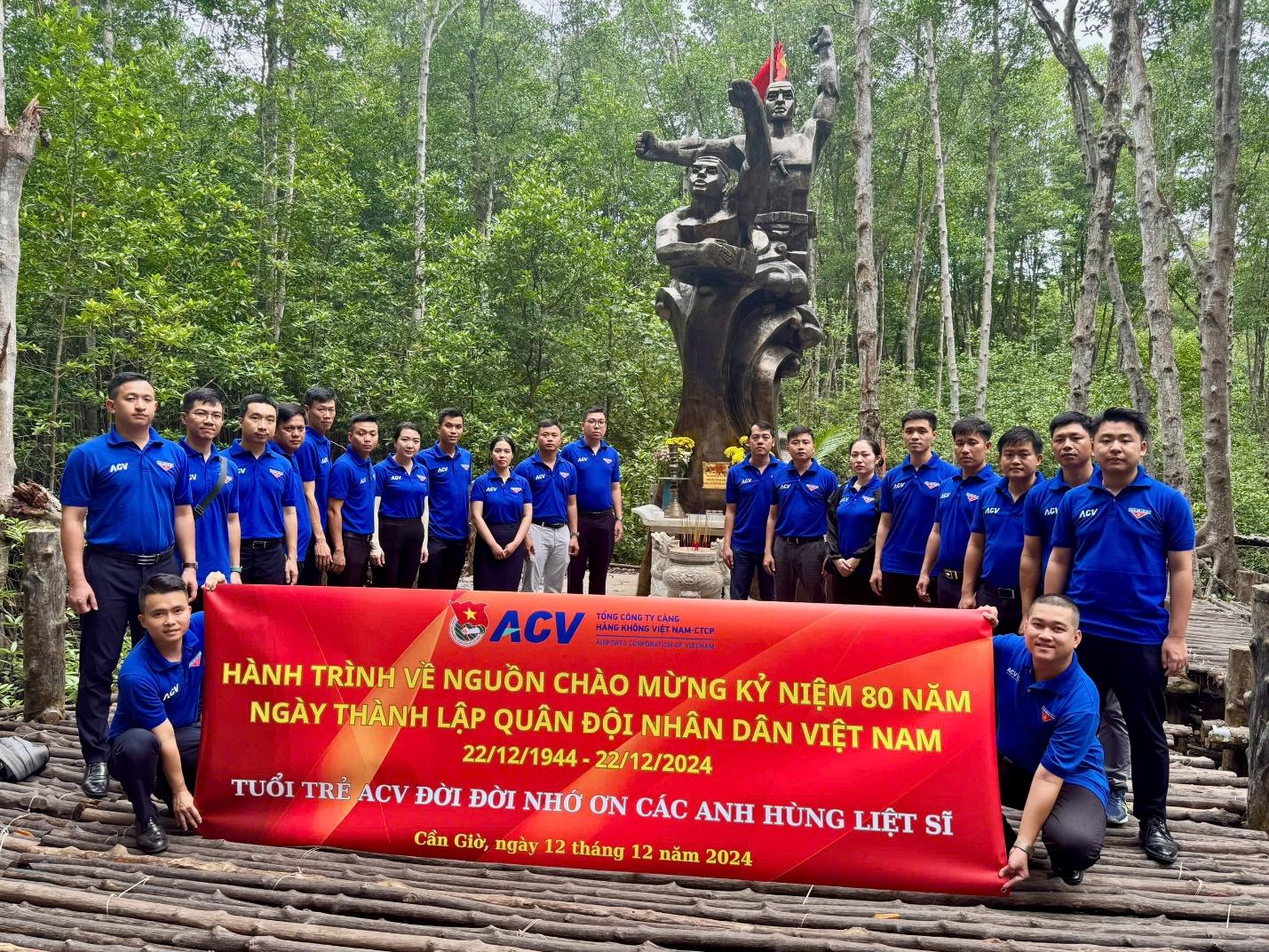 A group of people posing for a photo with a large bannerDescription automatically generated