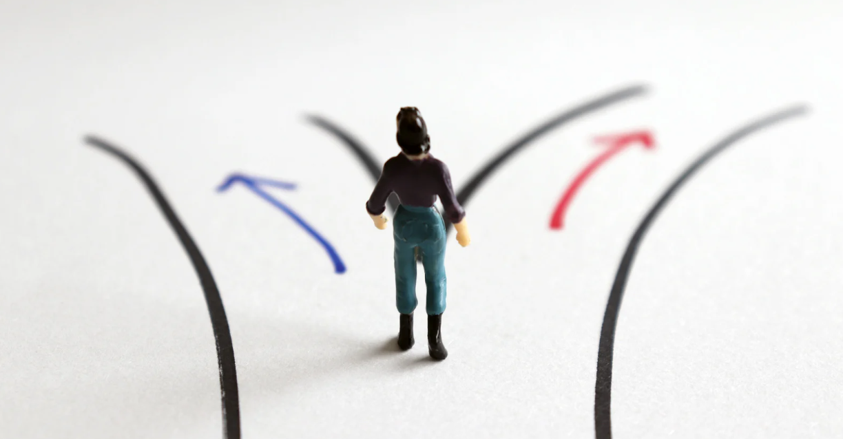 (A small figurine stands at a three-way fork in the road, symbolizing financial decision-making and choosing the right path out of debt.)
