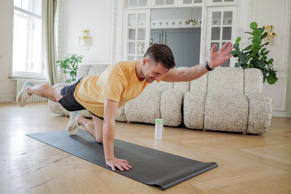 un barbat fericit imbracat sport face plank in living