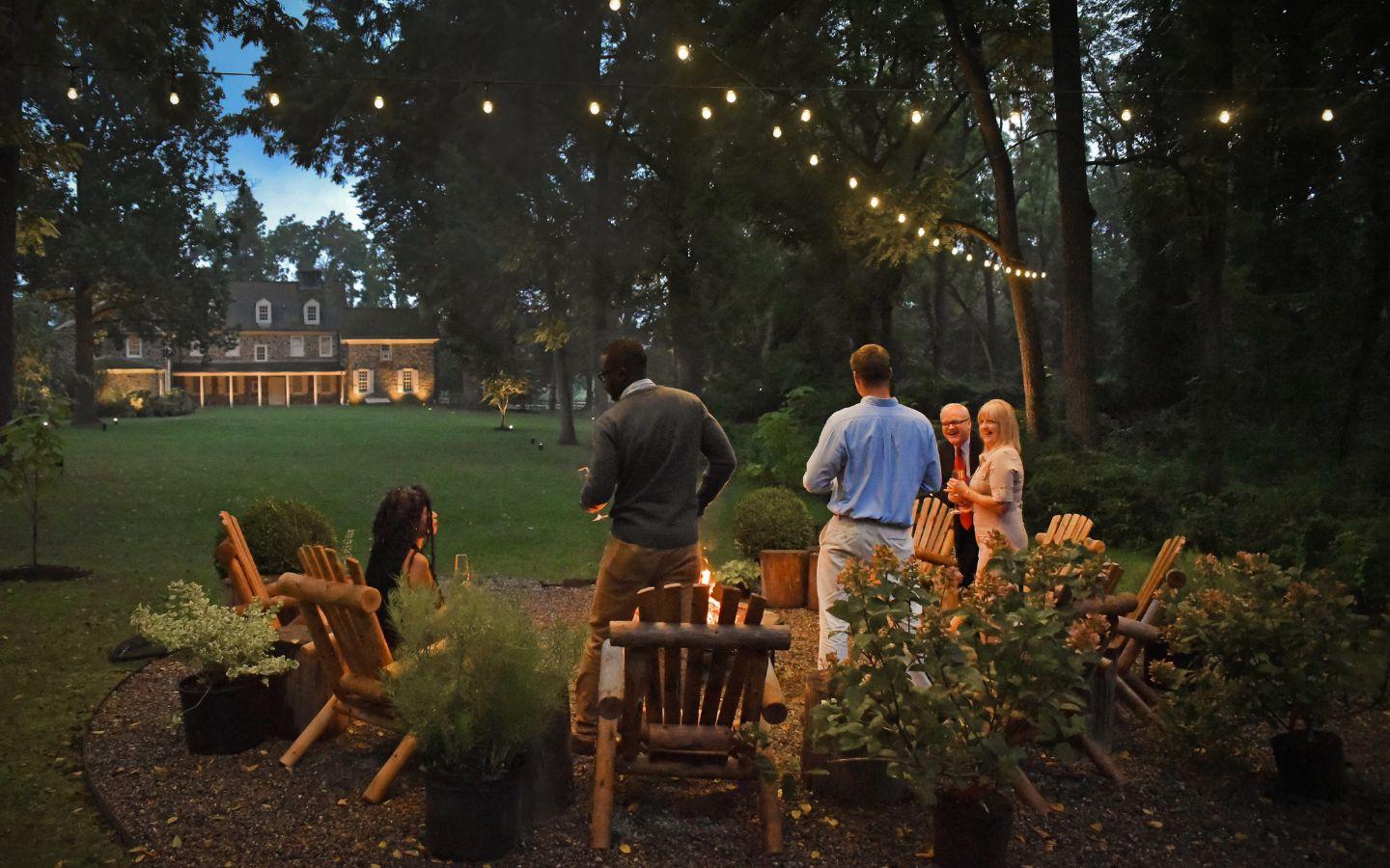 A group of people standing around a fire pit

Description automatically generated