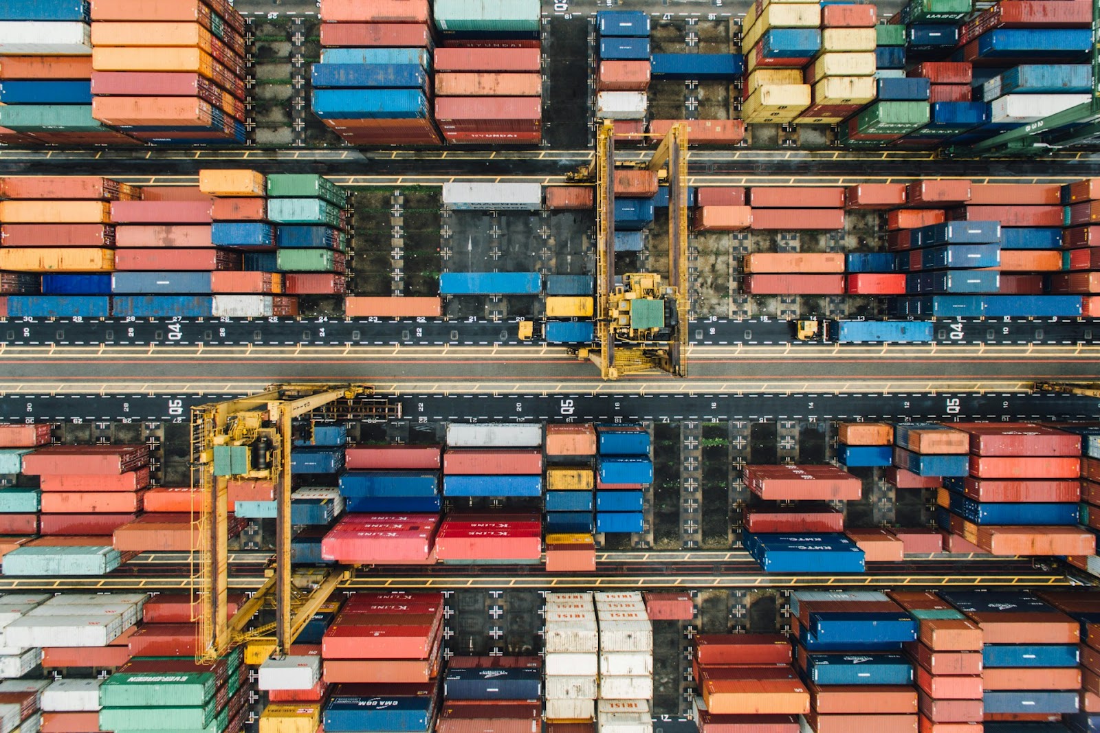 Overhead shot of colorful shipping containers neatly stacked in a busy port, showcasing their organized arrangement.