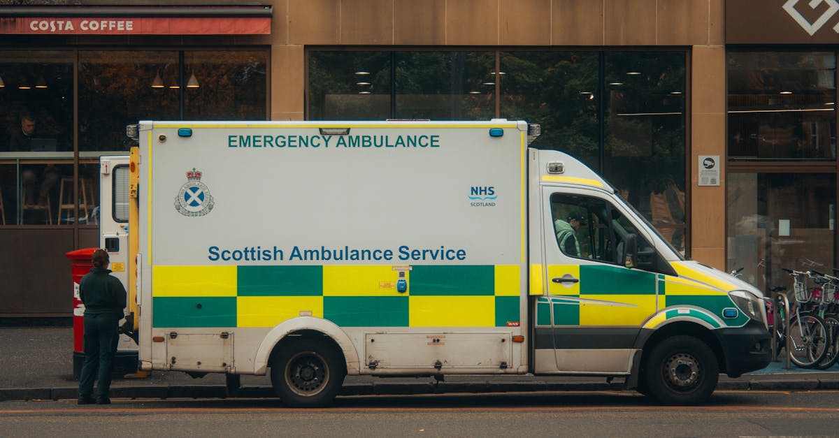 Scottish Ambulance Service vehicle parked on a city street with a pedestrian nearby.