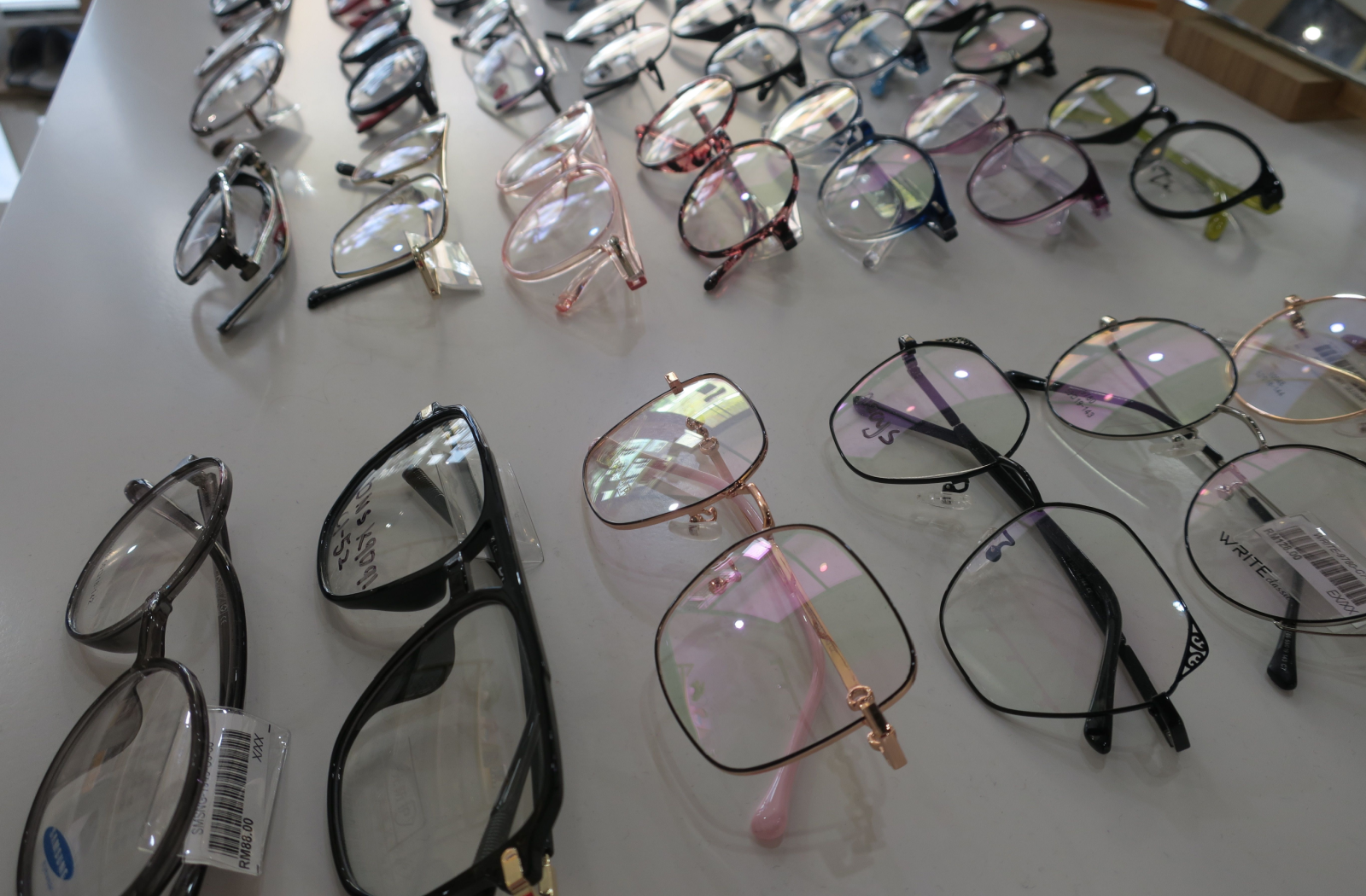 A shiny opticians counter displays over 20 varieties of eyeglass frames for patients.