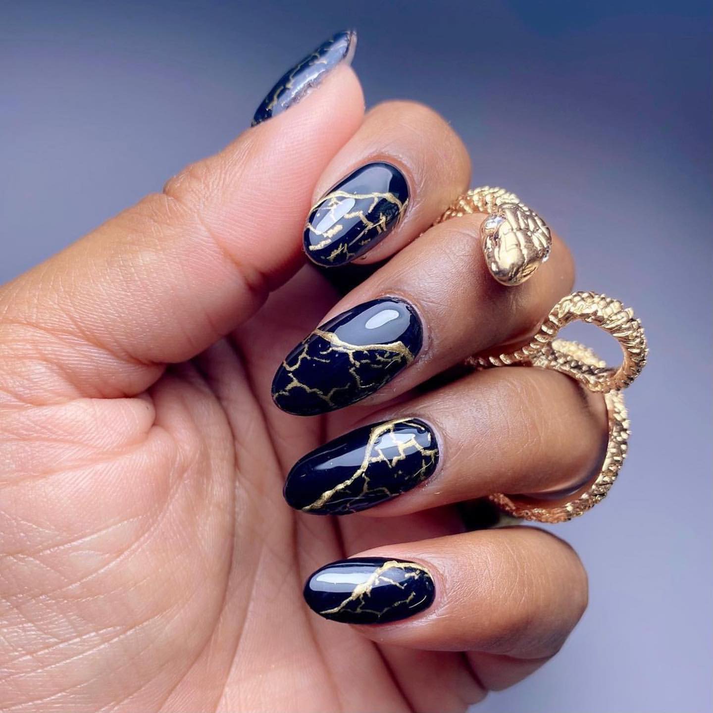 Close-up of a person's hands with black nails having Black and Gold Marbling