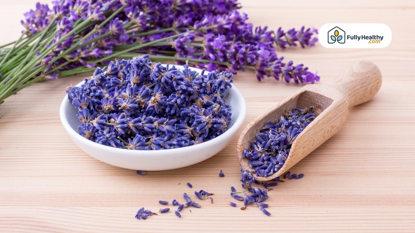 Dried lavender buds in bowl and scoop on wooden table surface