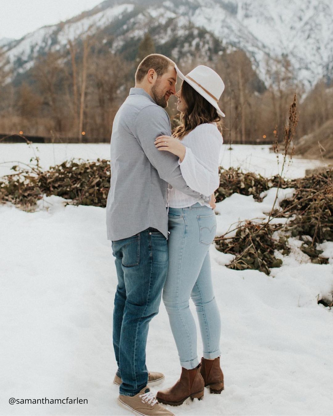 winter engagement photos couple hugs in snowy mountains