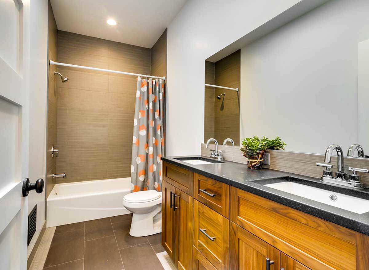 This bathroom has dual vanities, a toilet, and a tub and shower combo.