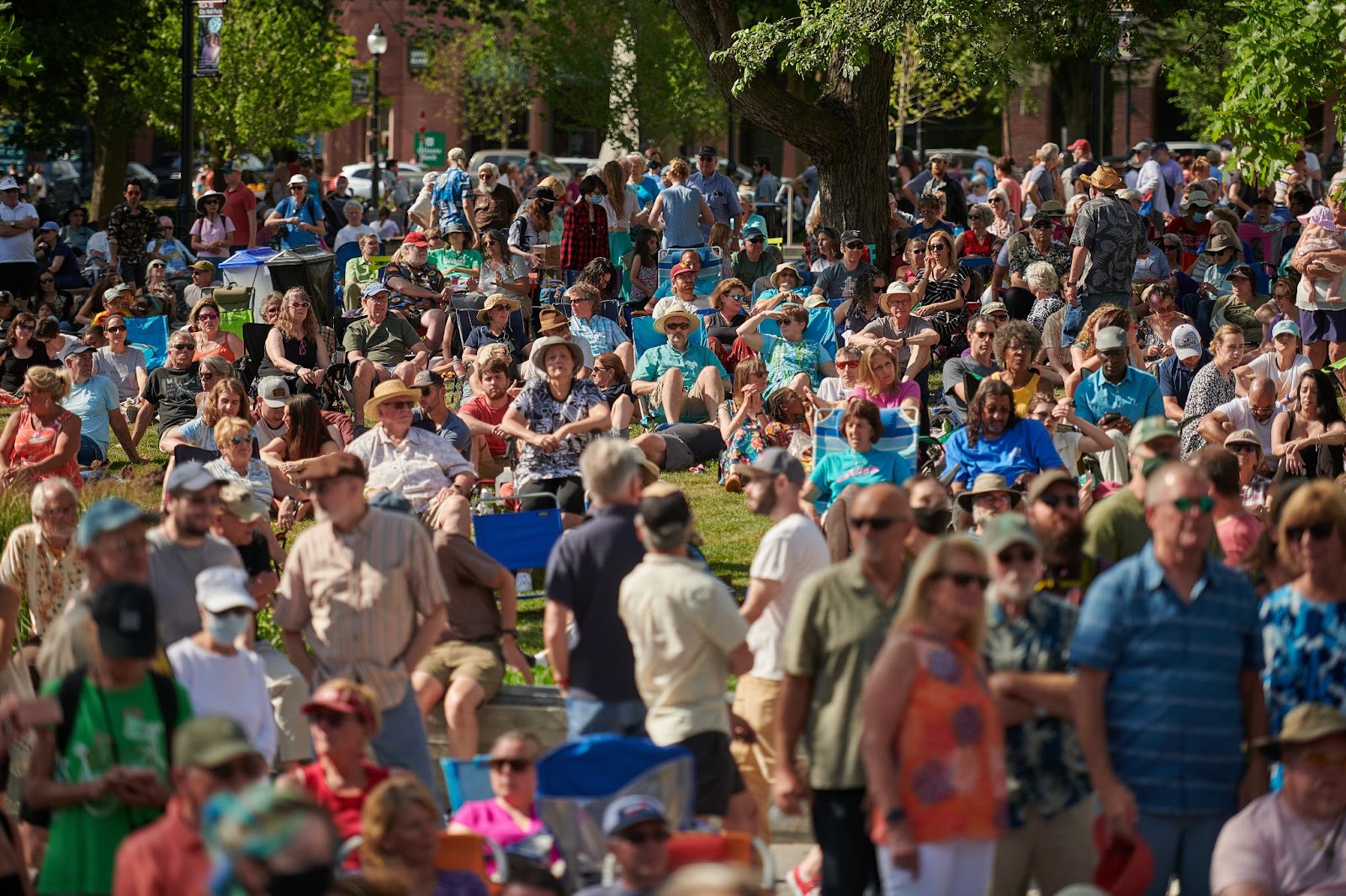 People sitting on lawn chairs and standing around City Hall Park during the Summer Concert Series in Burlington, VT.