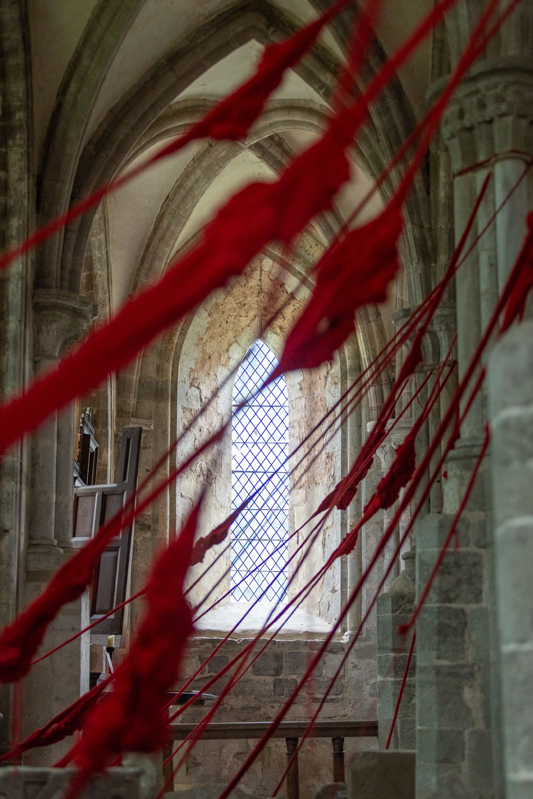 Red cloth strings in a church

Description automatically generated