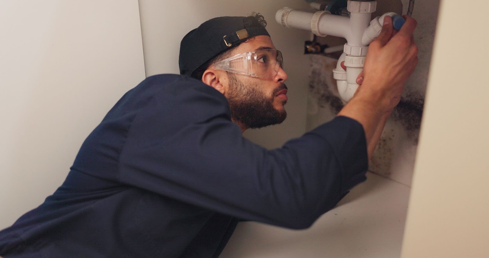 Plumber wearing goggles under a sink. 