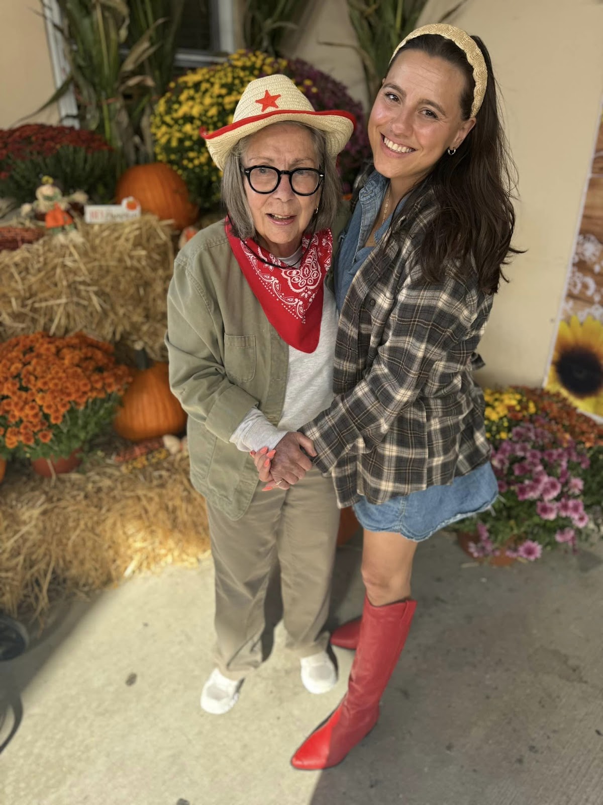 An assisted living resident and worker dressed in Fall attire in front of fall-related paraphernalia 